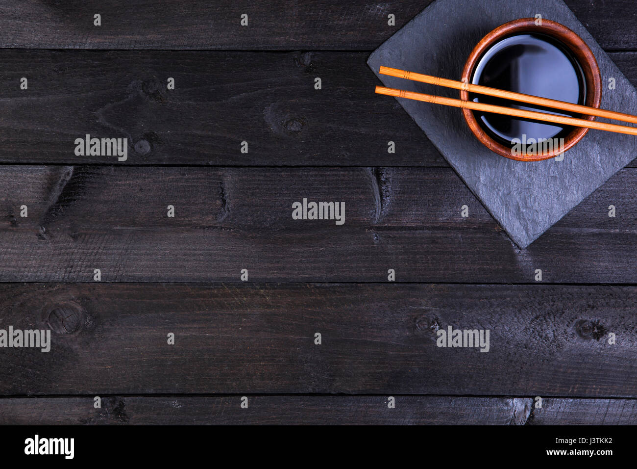 Sushi-Stäbchen und Sojasauce auf schwarzem Hintergrund. Draufsicht mit Textfreiraum. Stockfoto