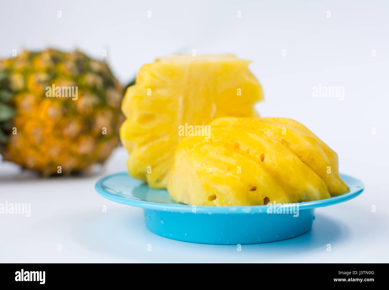 Geschälte und geschnittene Ananas auf einem blauen Teller Stockfoto