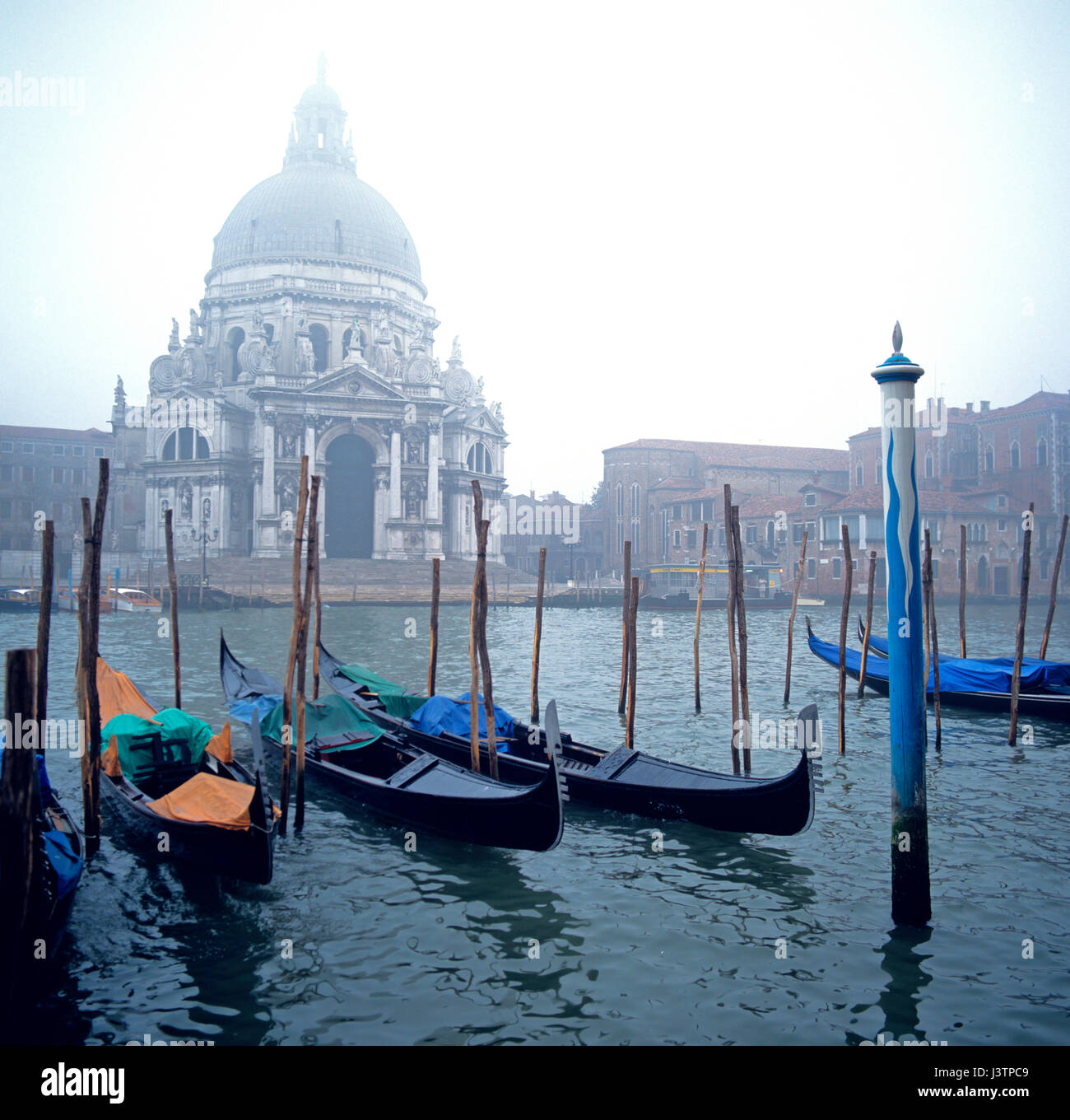 Venedig einen Blick über die Lagune, die Kirche Santa Maria della Saute im Morgennebel mit Gondeln auf ihren Liegeplatz Masten mit Vordergrund focu Stockfoto