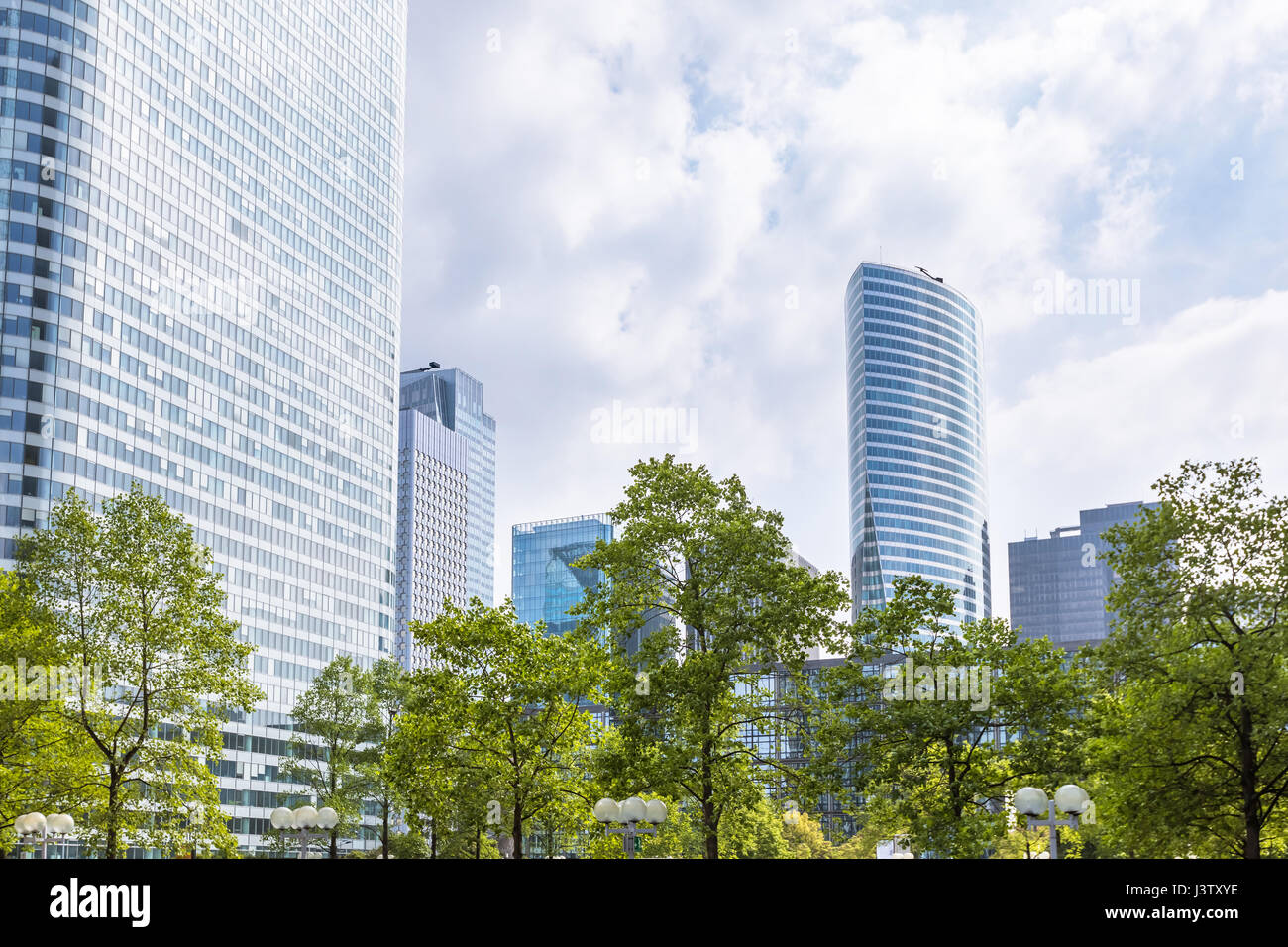 Moderne Geschäfts- und Finanzzentrum mit grünen Bäumen und Laub und Wolkenkratzer mit Glasfassade, Frühling in La Défense, Paris Stockfoto