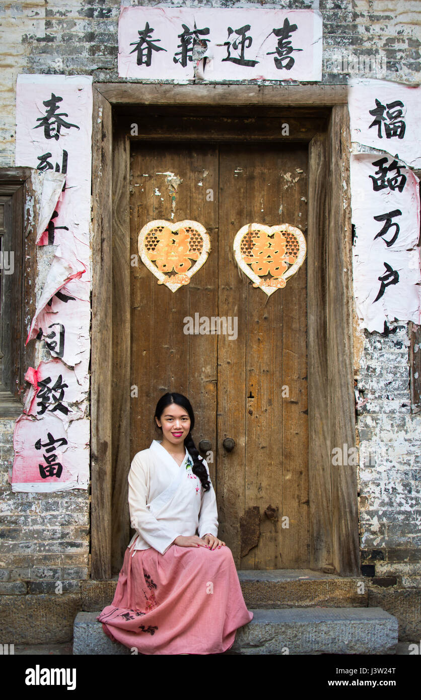 Mädchen sitzen vor alten chinesischen Türen Stockfoto