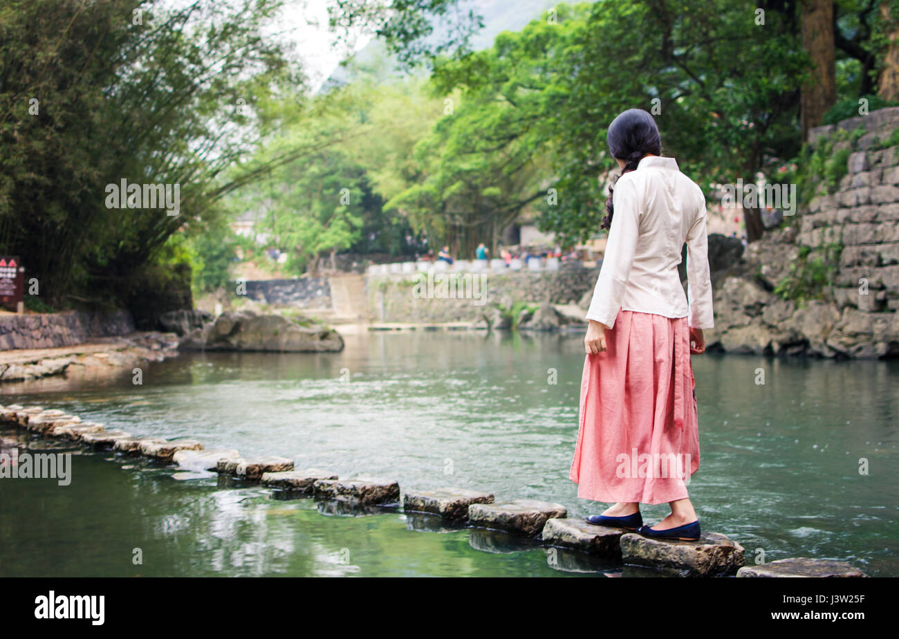 Mädchen zu Fuß auf kleine Steinbrücke im Fluss Stockfoto