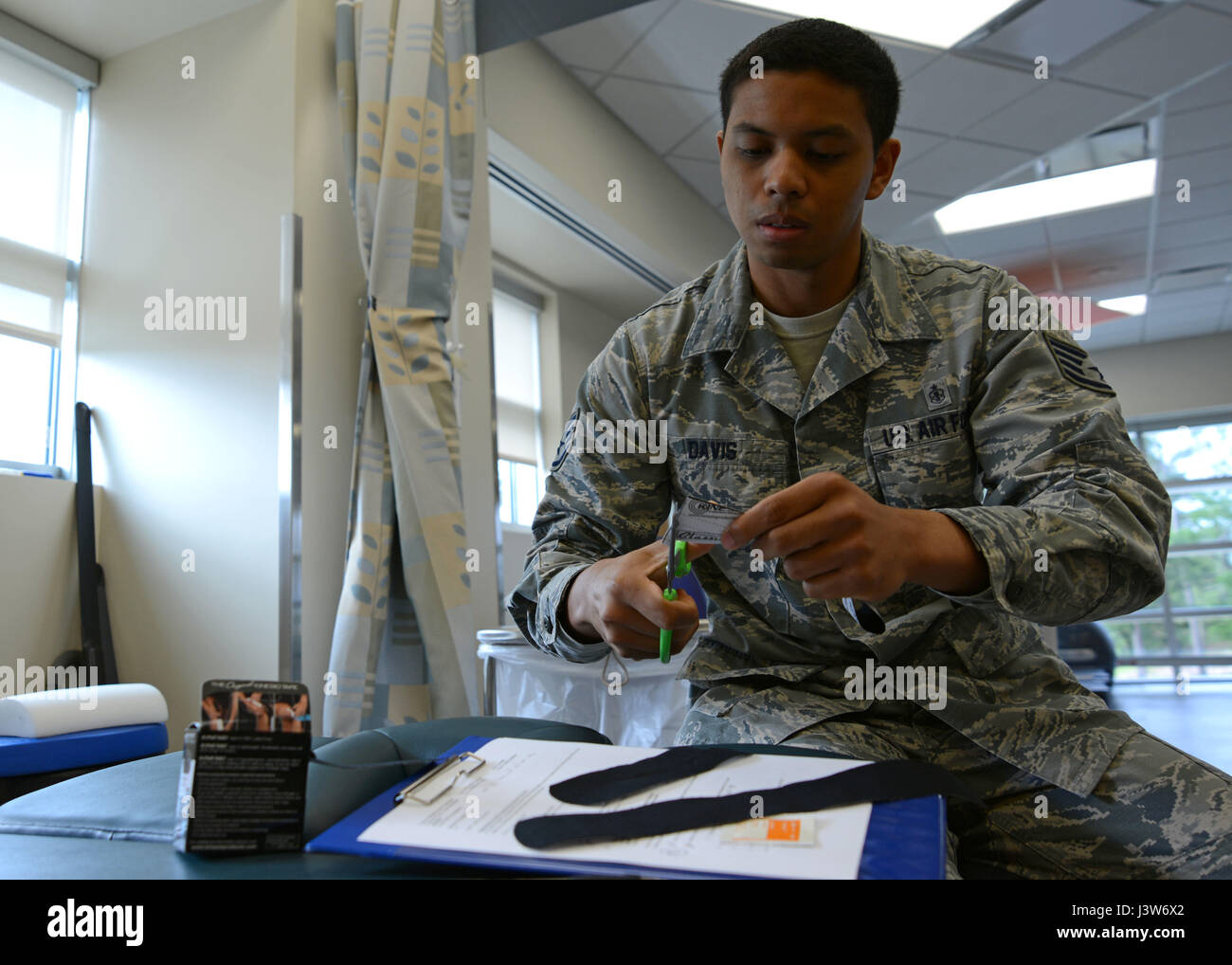 US Air Force Staff Sgt Marco Davis, 20. medizinische Operations Squadron-physikalische Medizin-Techniker, schneidet Kinesio Tape in der Physiotherapie Klinik Shaw Air Force Base, S.C., 1. Mai 2017. Davis angewendet das Band am Patienten zu therapeutischen Zwecken, z. B. Ausrichten der Muskeln, Gelenke zu stabilisieren und Verbesserung der Durchblutung. (Foto: U.S. Air Force Airman 1st Class Kathryn R.C. Reaves) Stockfoto