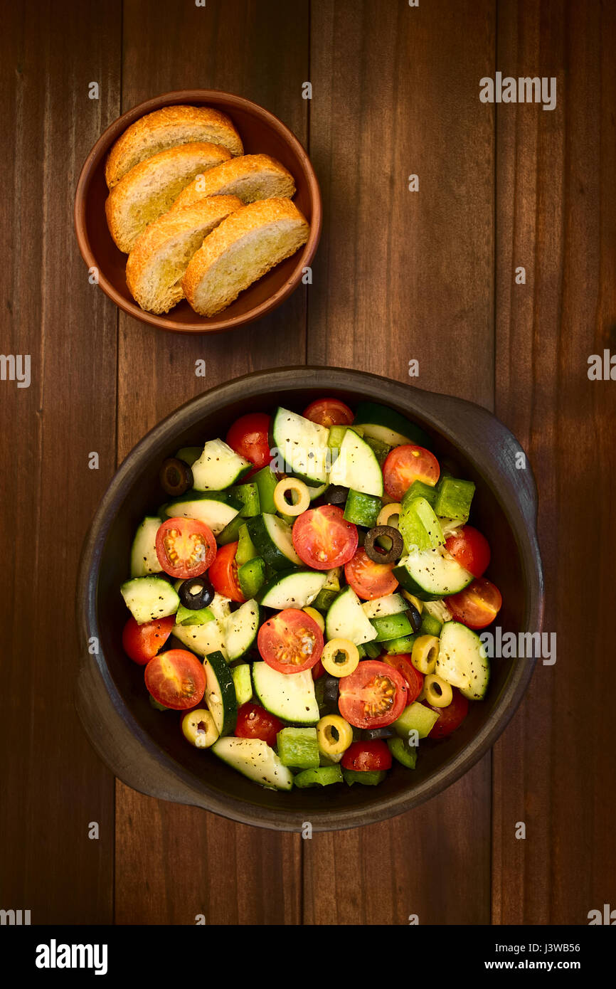 Der schwarze und grüne Oliven, Cherry-Tomaten, grüne Paprika und Gurken, frischer Salat, gewürzt mit Salz, Pfeffer, getrockneter Oregano und Basilikum Stockfoto