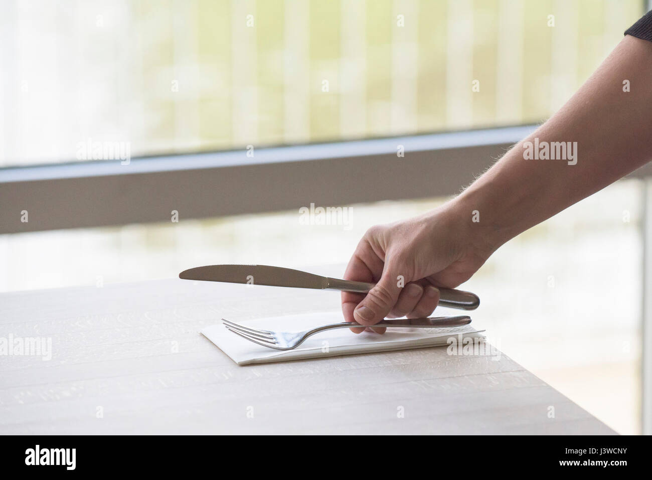Besteck platziert auf einem Tisch im Restaurant Messer und Gabel Serviette Serviette Einstellung eine Tabelle Kellnerin Hand Arm Stockfoto