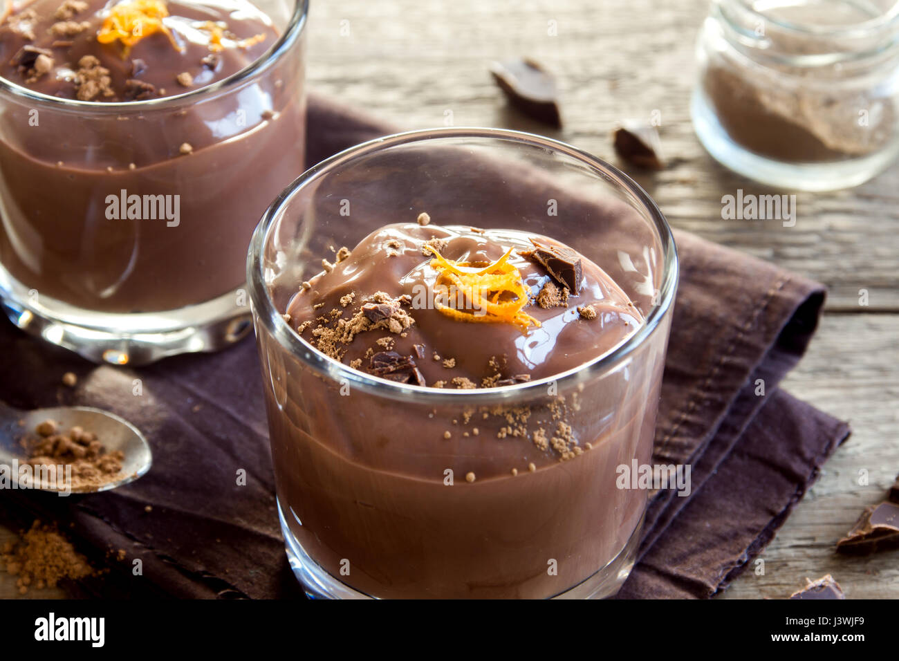 Schokoladenmousse garniert mit Orange Zest in Gläsern über hölzerne Hintergrund schließen sich - köstliche hausgemachte Schokoladenpudding Stockfoto
