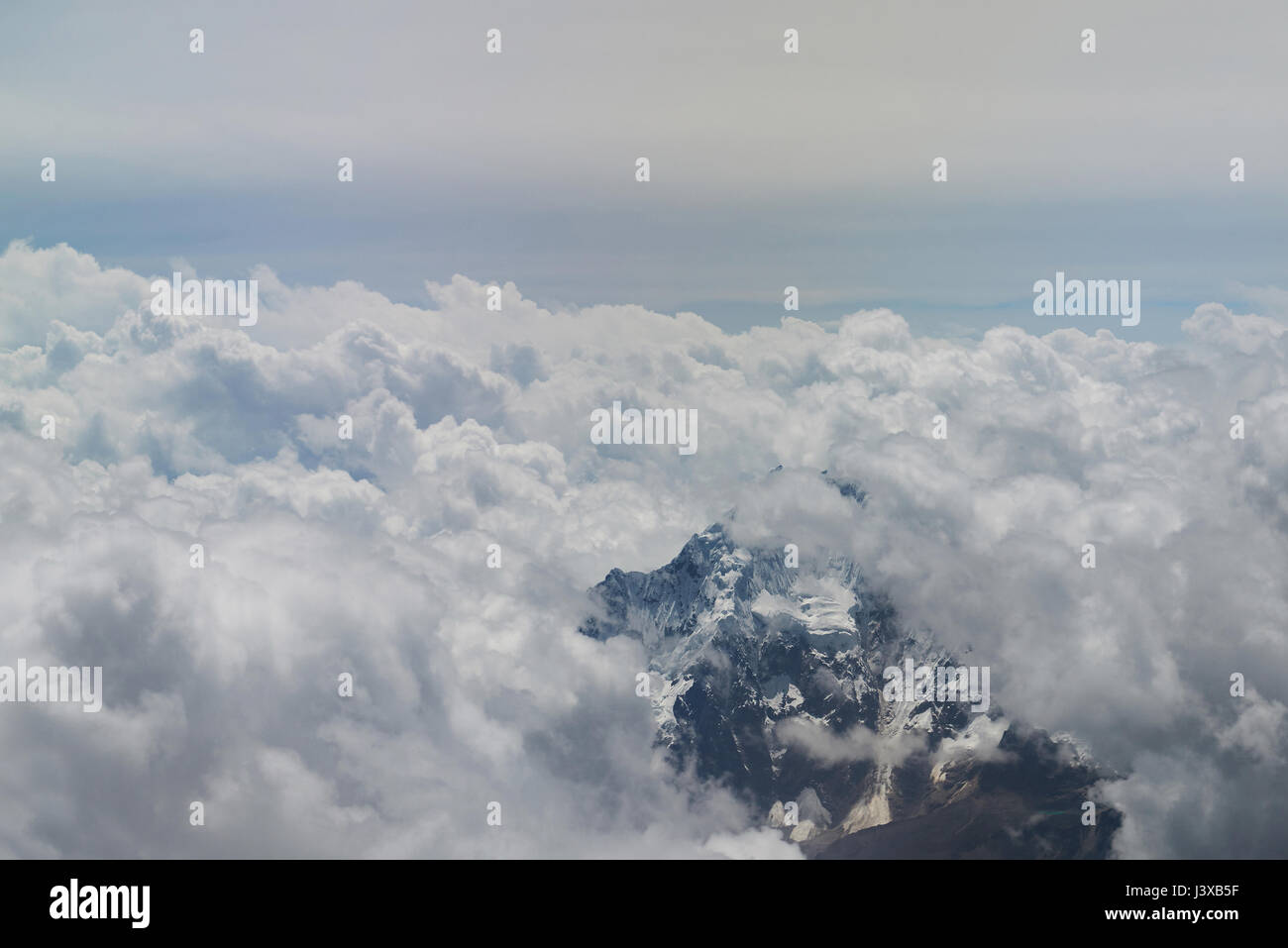 Verschneite Berggipfel rund um weiße Wolken Luftbild Stockfoto
