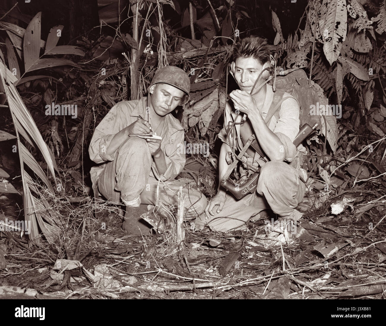 Navajo Code Talkers bei Bougainville im Dezember 1943 während des zweiten Weltkriegs. Betreiben Sie Korporal Henry Backen Jr (links) und Private First Class George H Kirk (rechts), serviert mit einer Marine Signaleinheit, ein tragbares Radio inmitten einer Lichtung, die sie in den dichten Dschungel nahe hinter den Frontlinien gehackt habe. Stockfoto