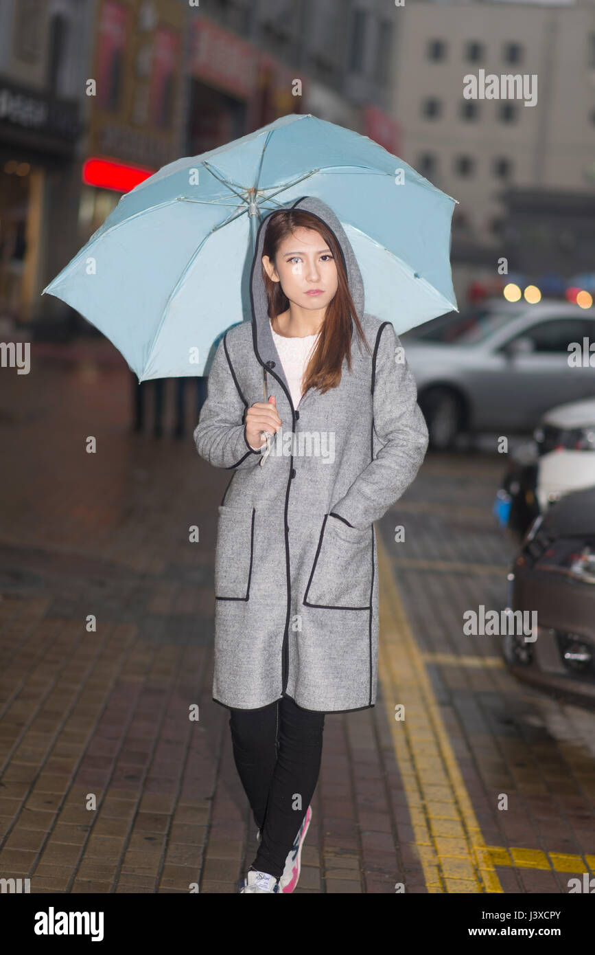 Frau ist in der Nacht Spaziergang im Regen mit blauen Schirm Stockfoto