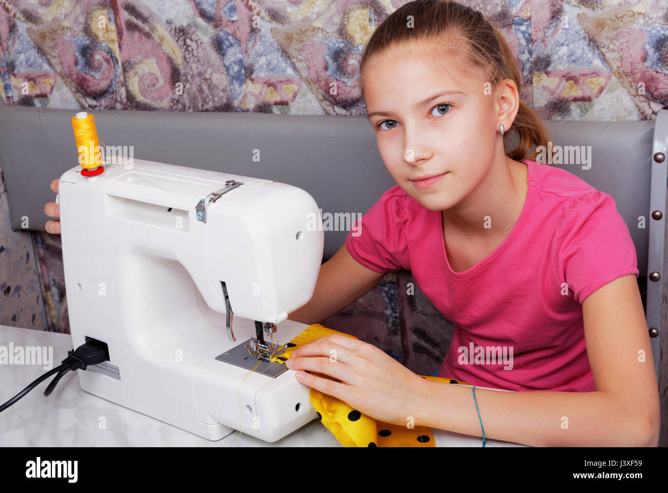 Mädchen lernt auf eine elektrische Nähmaschine nähen Stockfoto