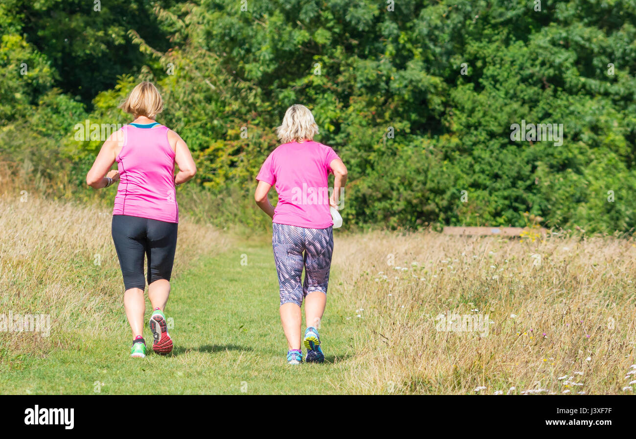 Paar der weiblichen Jogger Joggen durch die Felder in der britischen Landschaft. Konzept der Ausübung. Keeping fit Konzept. Stockfoto