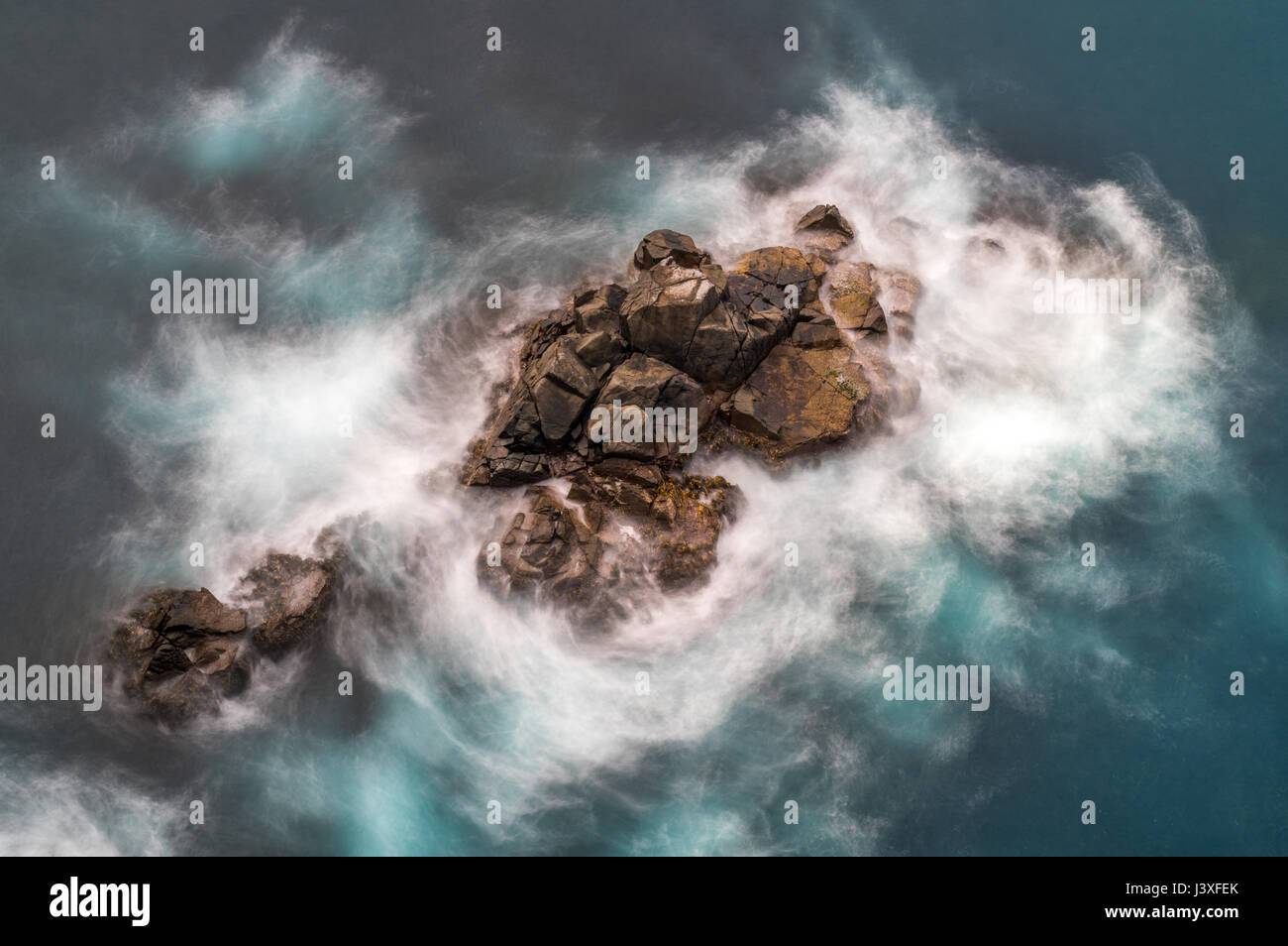 Ein Felsen, umgeben von Wildwasser, mit einem Gefühl der Bewegung und Gewalt. Stockfoto