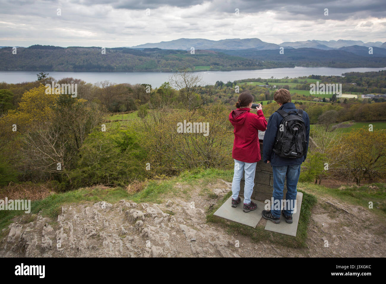 Ein paar stehen auf die Oberseite Orrest Head außerhalb Windemere im Lake District, mit Blick auf die Aussicht und die Fotos von den Bergen am Horizont. Stockfoto