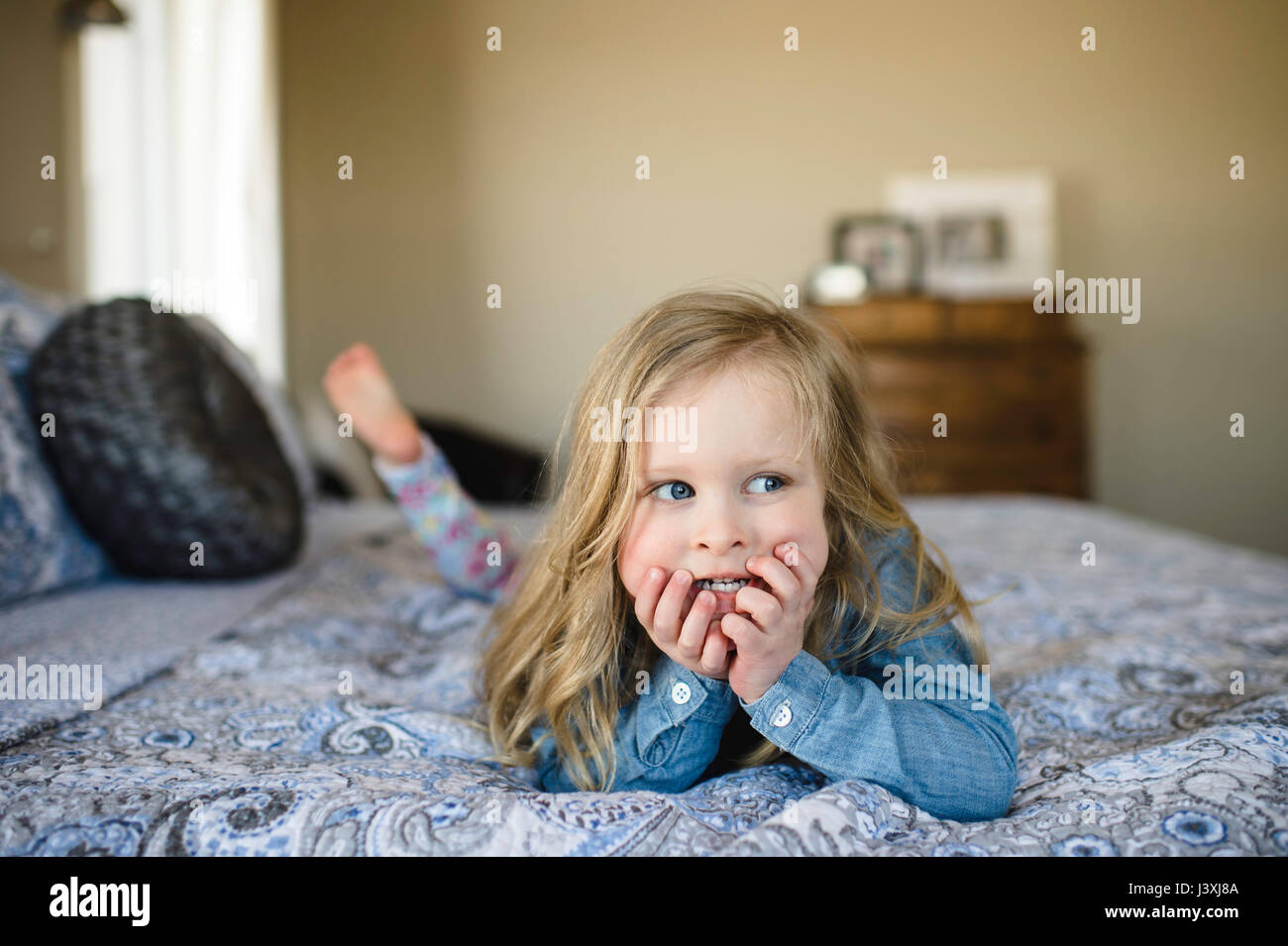 Mädchen auf Bett Blick seitlich liegend Stockfoto