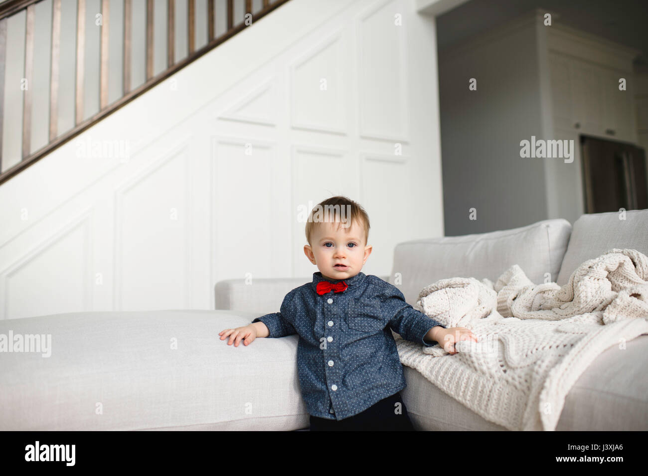 Portrait der männlichen Kleinkind in red Bow Tie gegen Sofa lehnend Stockfoto