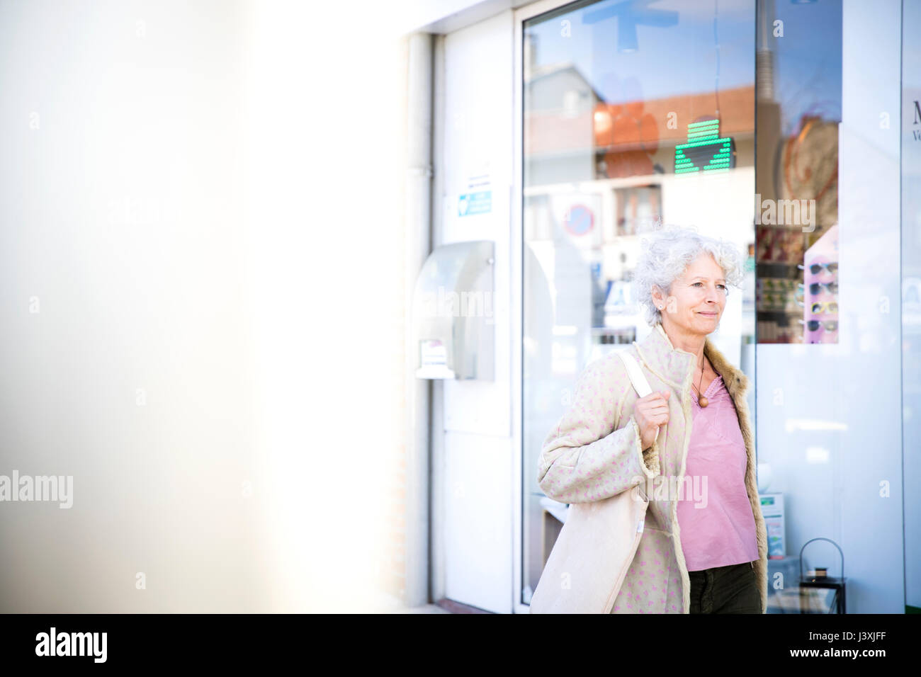 Reife Frau Shopper vorbei an lokalen bank Stockfoto