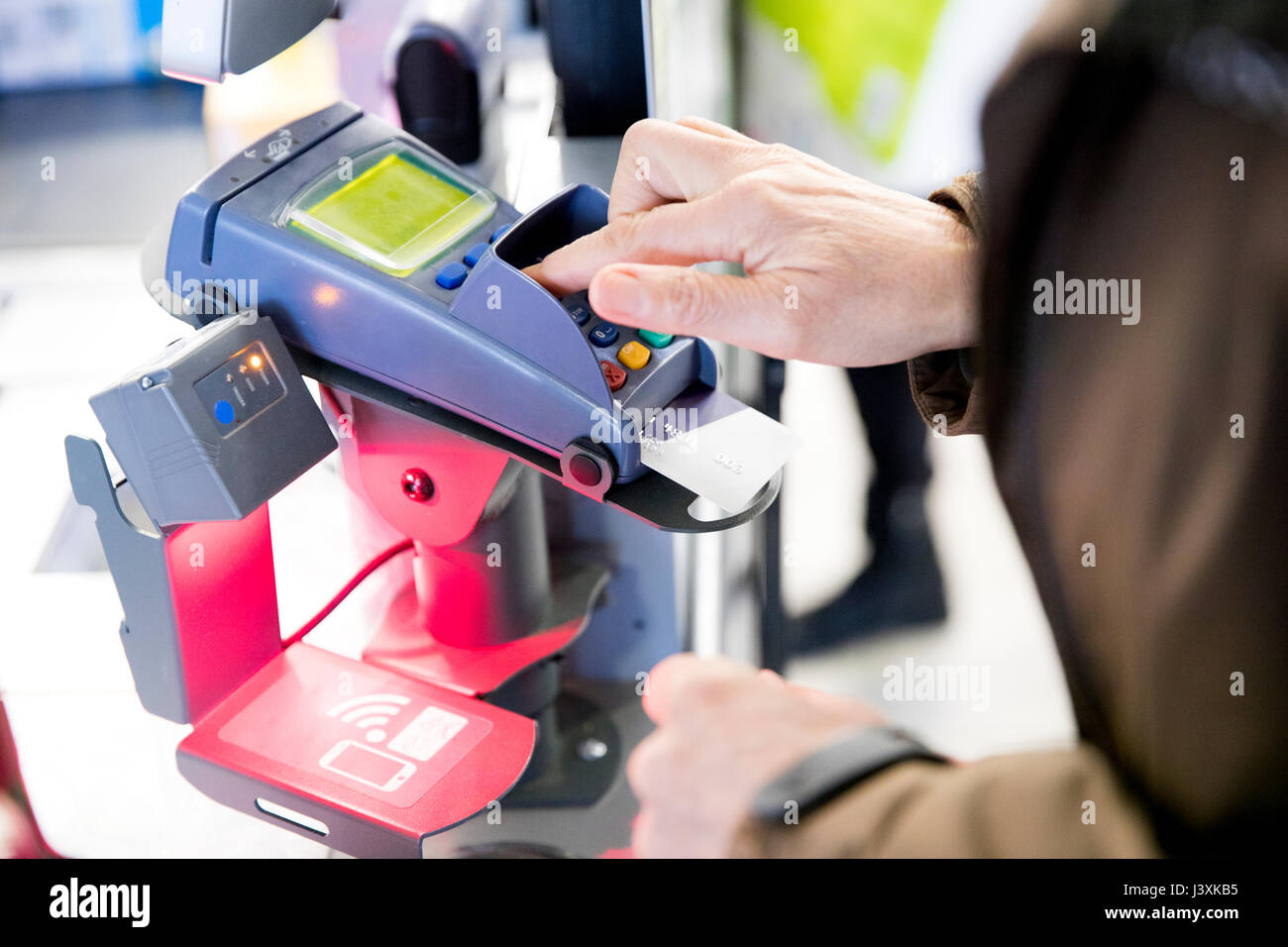 Reife Frau mit Kreditkarte Maschine für den Einkauf zu bezahlen, close-up Stockfoto