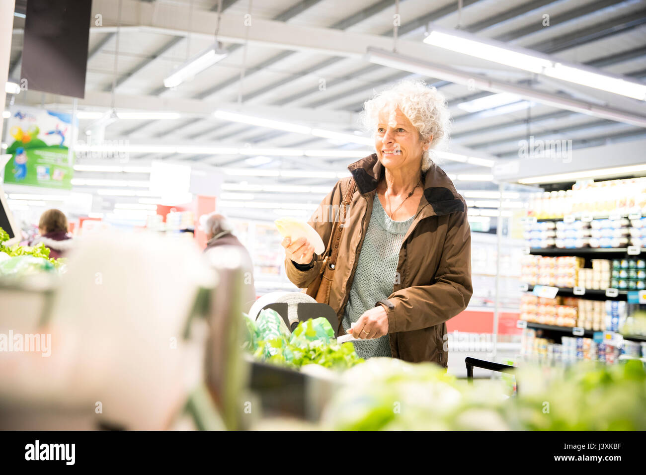 Reife Frau im Supermarkt, der frische Produkte Stockfoto