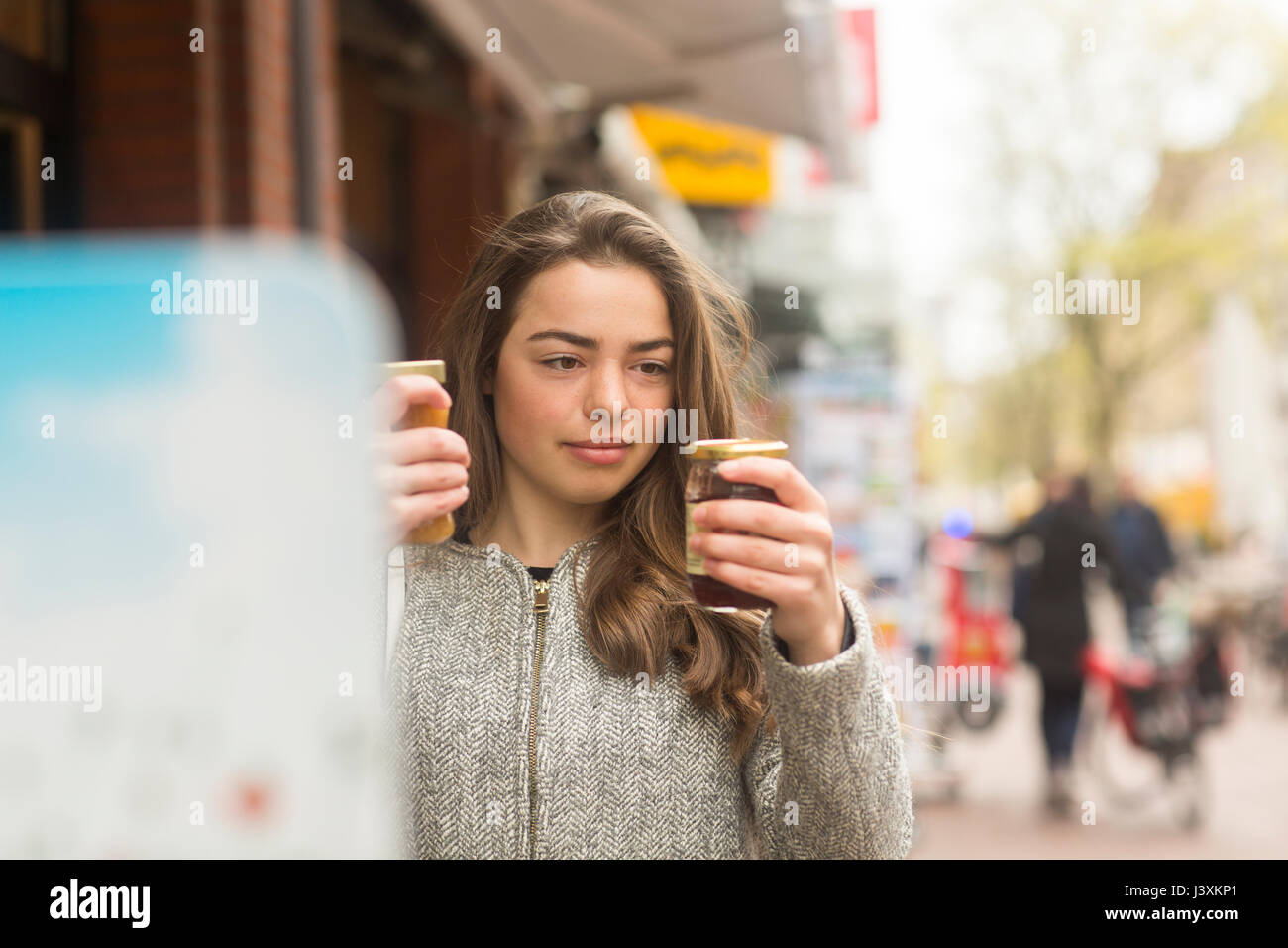 Junge Frau vergleich Gläser am Markt bewahren Abschaltdruck Stockfoto