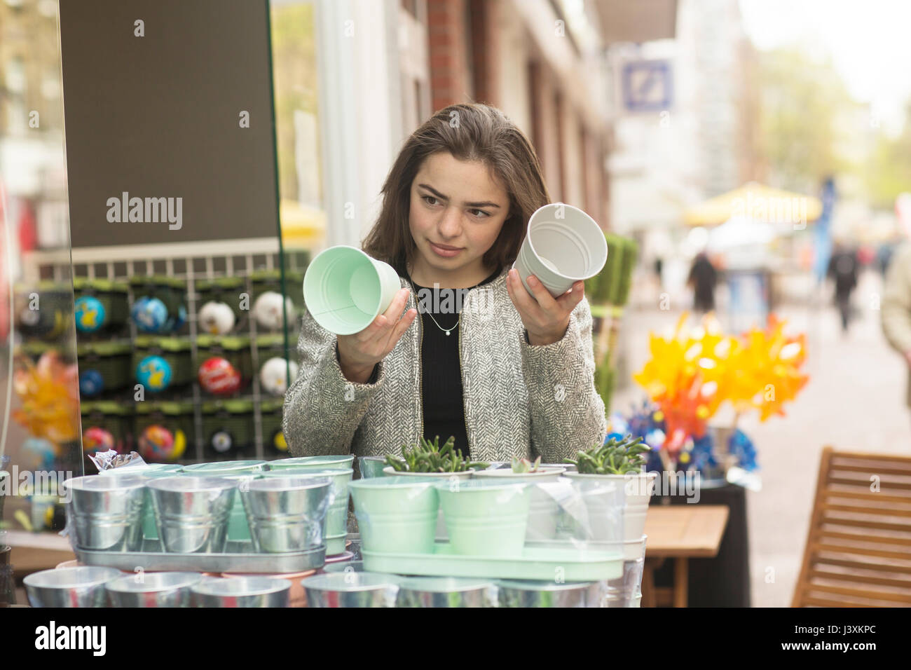Junge Frau vergleich Blumentöpfe auf Marktstand Stockfoto
