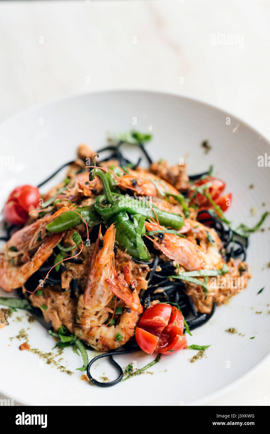 Gourmet-Essen gegrillte Garnelen und Gemüse auf schwarzen Tintenfisch Tinte Nudeln Essen Stockfoto