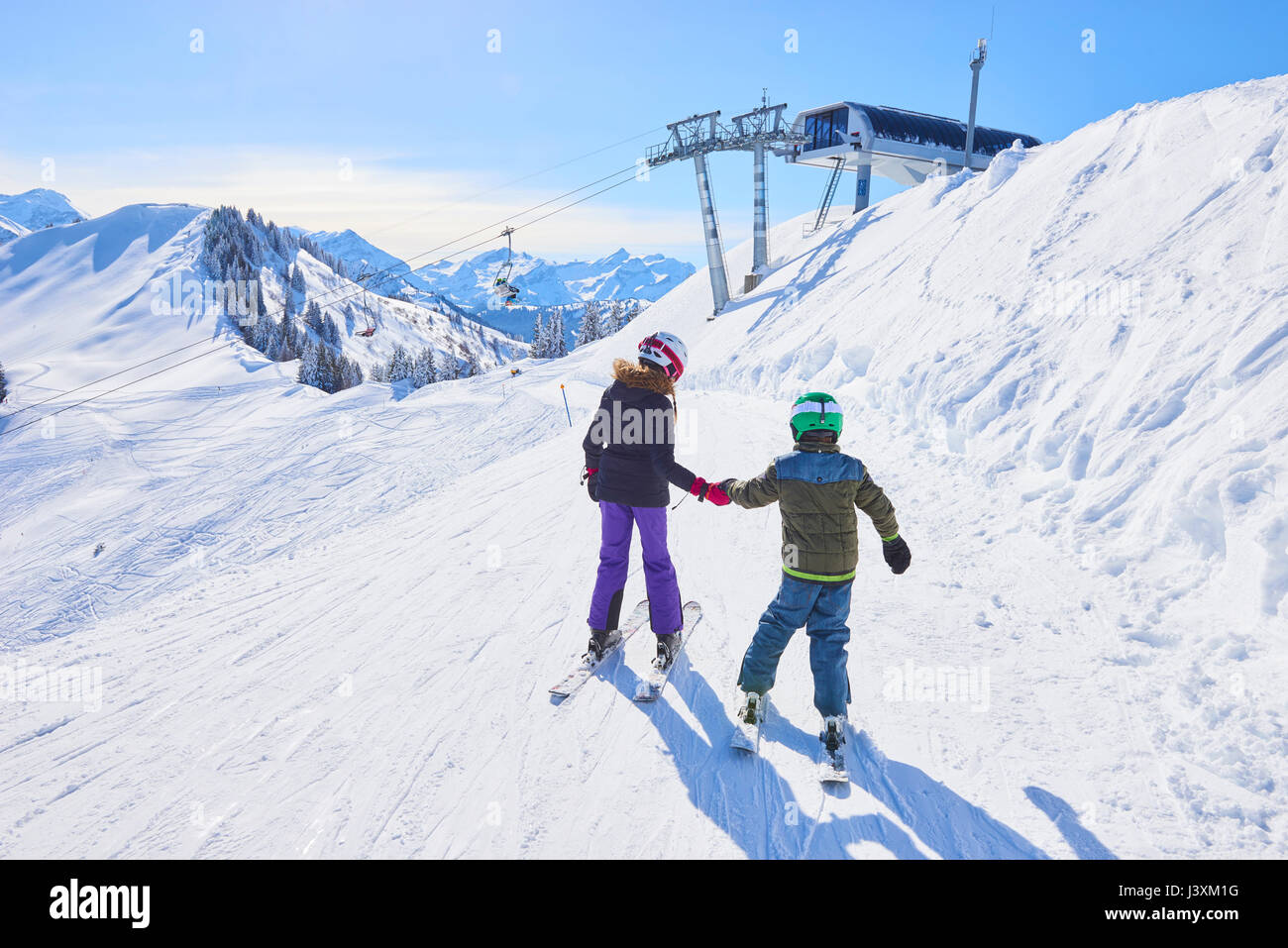 Ansicht der Rückseite des Mädchens und Bruder, Hände auf Skipiste, Gstaad, Schweiz Stockfoto