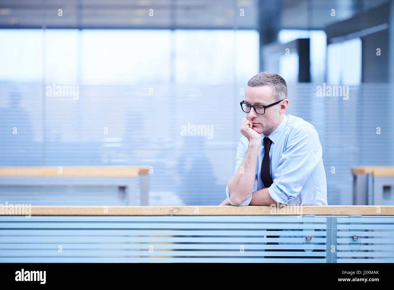 Betonte Geschäftsmann mit Kinn auf Hand in Büro atrium Stockfoto