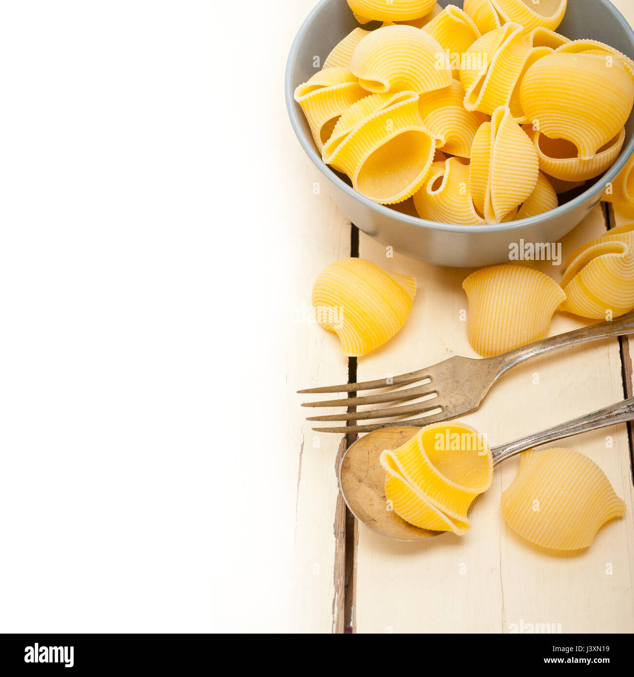 rohe italienische Schnecke Lumaconi Nudeln auf einer blauen Schüssel über rustikalen Tisch Makro Stockfoto