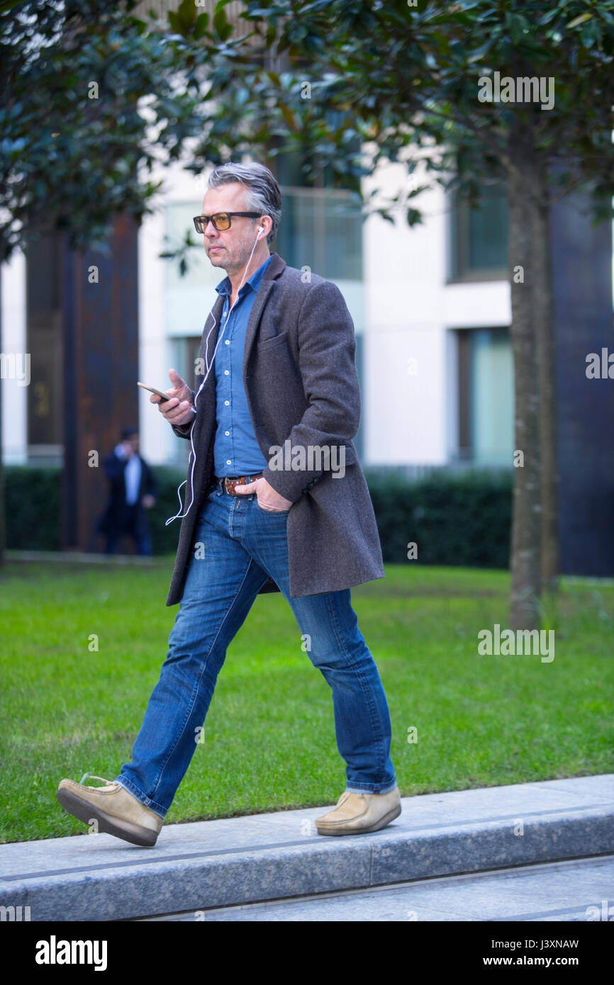 Mann mit Smartphone und Ohrhörer walking im freien Stockfoto