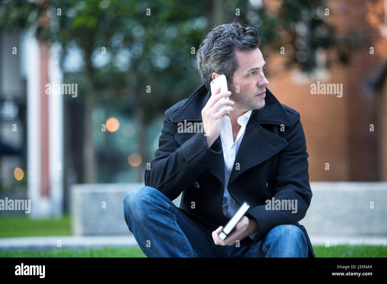 Mann, Gespräch mit Smartphone sitzen im Freien Stockfoto