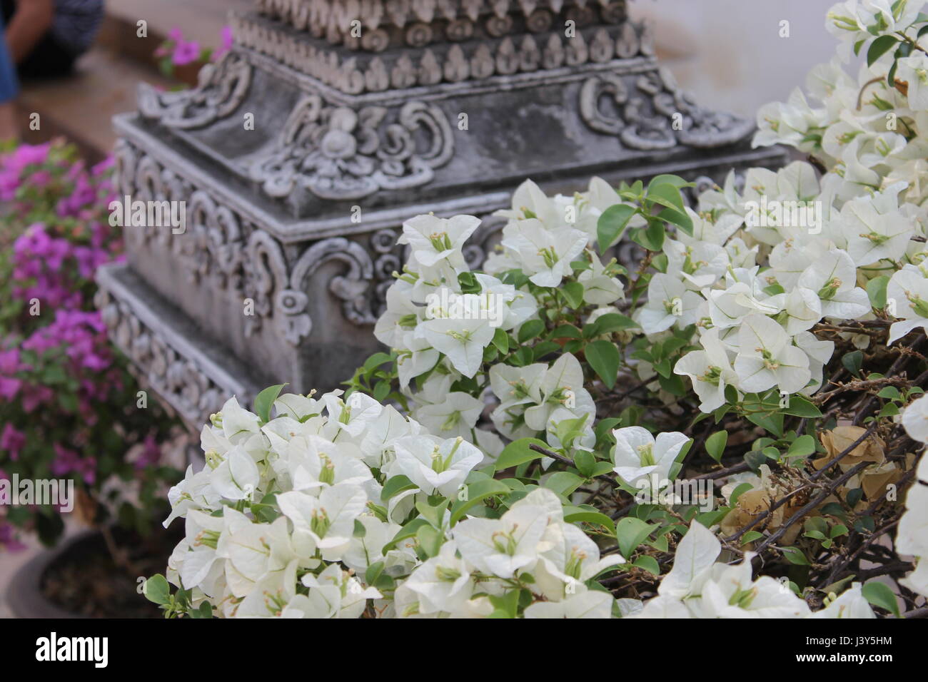 Blumen rund um geschnitzte Säule, Thailand. Stockfoto