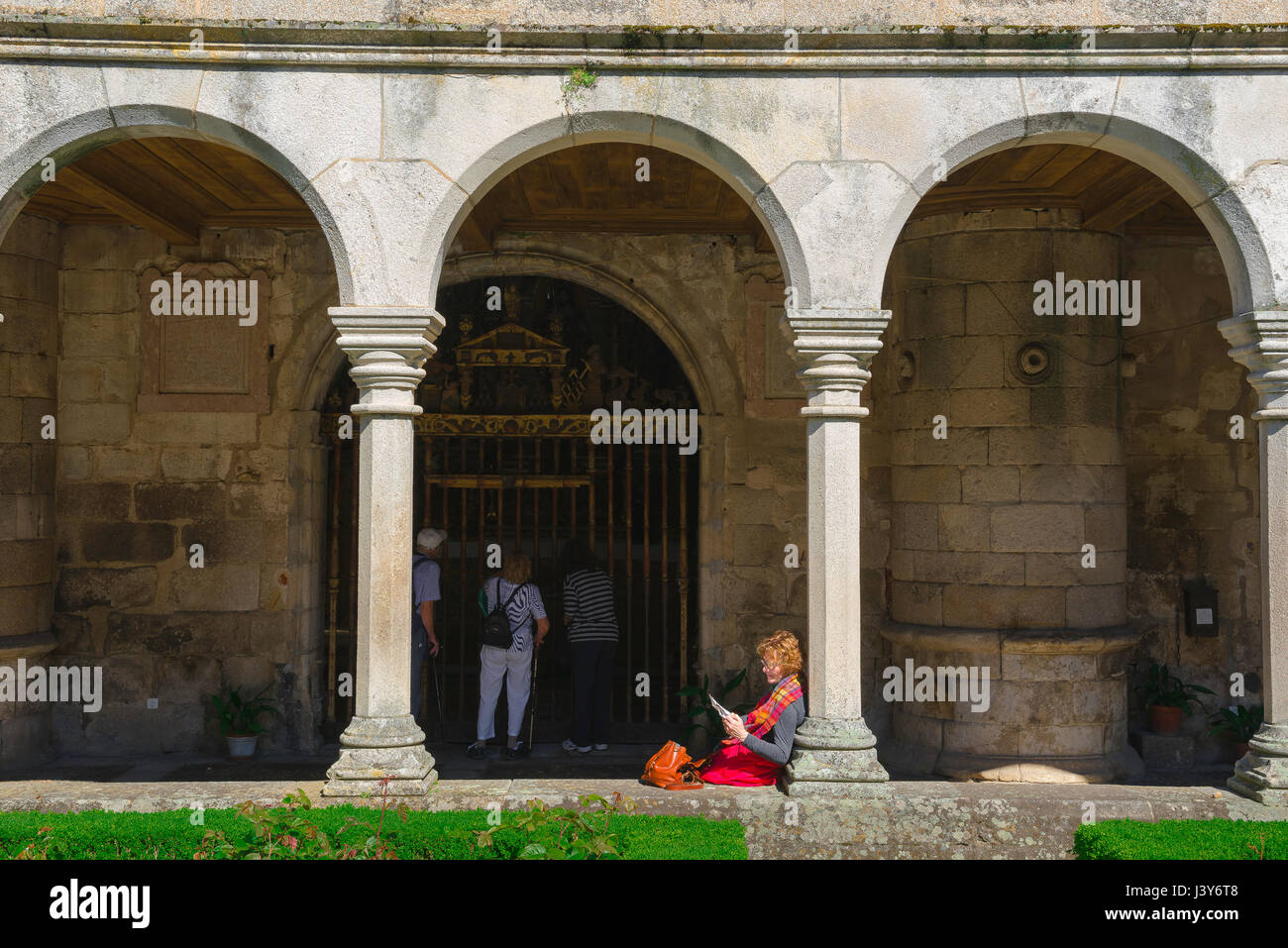 Frau, die Buch liest, Ansicht einer Frau mittleren Alters, die ein Buch liest, während sie allein in einem Kathedralenkloster in Portugal sitzt. Stockfoto