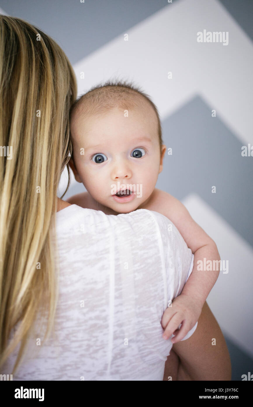 Über die Schulter-Porträt von niedlichen Baby Boy in Mutters Armen Stockfoto