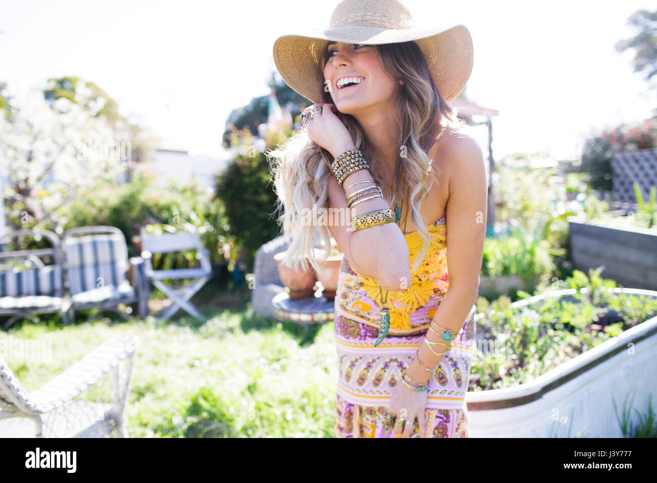 Glückliche junge Frau im Boho-Stil im Garten nach vorne lehnen Stockfoto