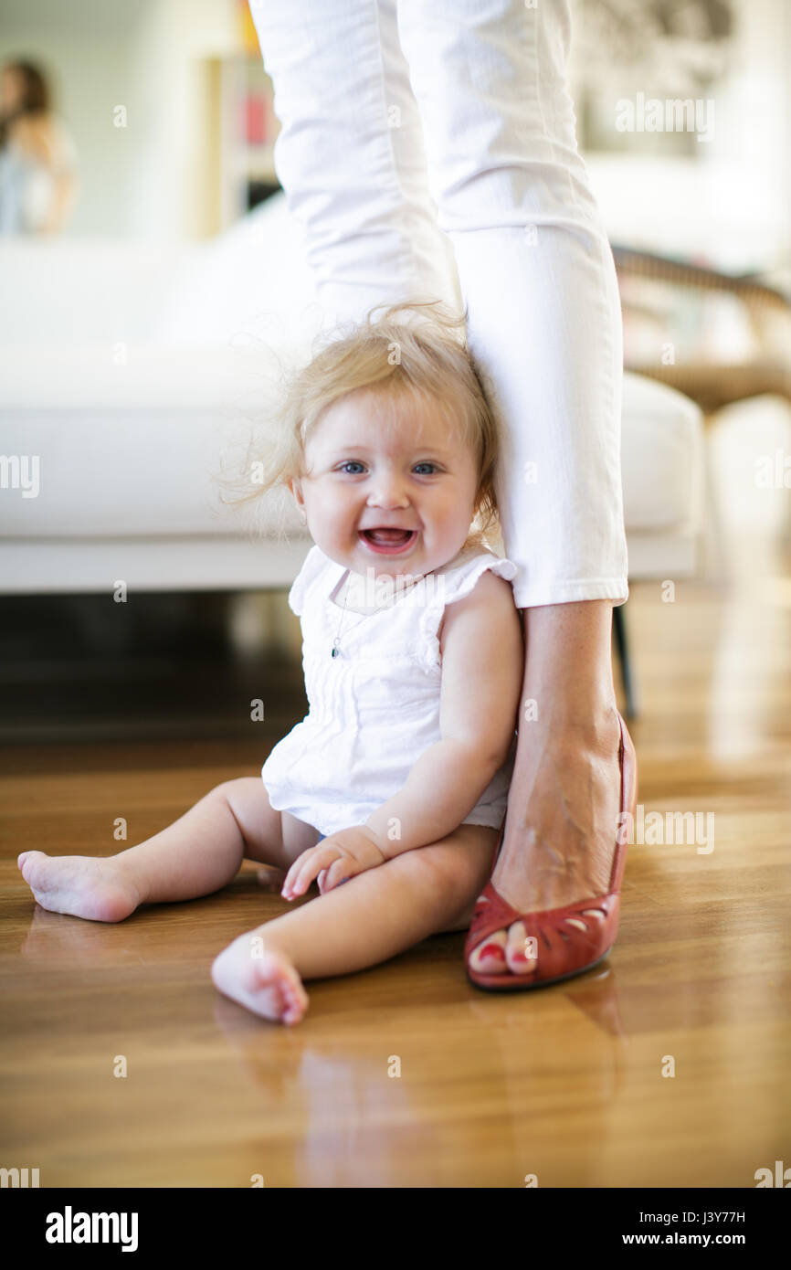 Porträt von Babymädchen sitzen auf dem Boden zwischen den Beinen Mutter Stockfoto