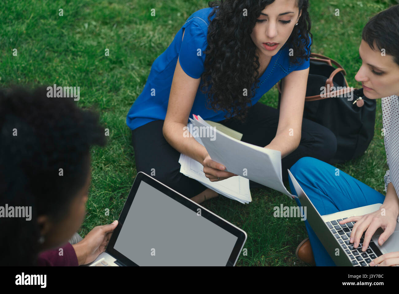 Drei Frauen sitzen auf dem Rasen, Studium, mit Notebooks Stockfoto