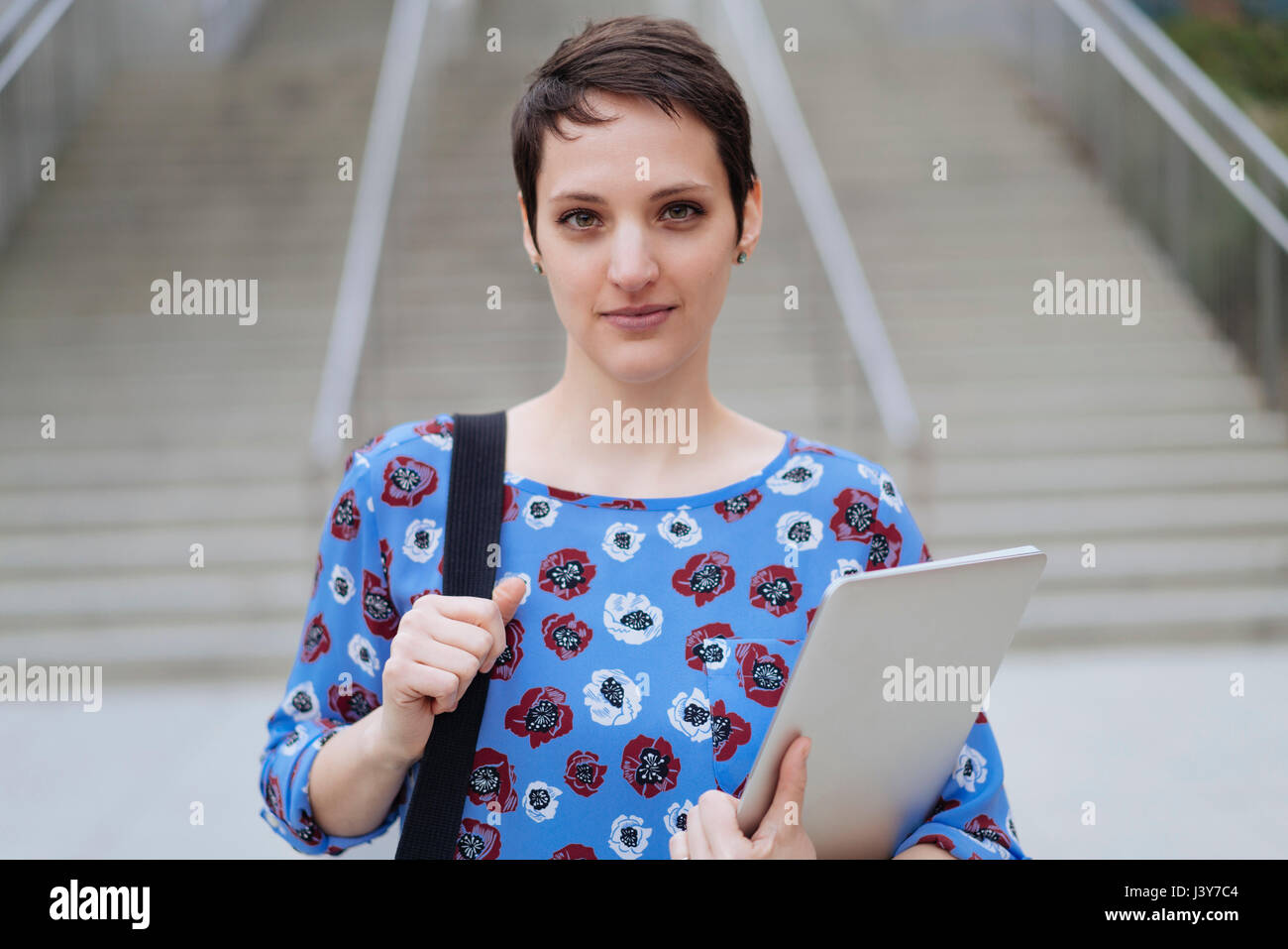 Porträt von Mitte Erwachsene Frau im Freien stehen, hält Tasche und laptop Stockfoto