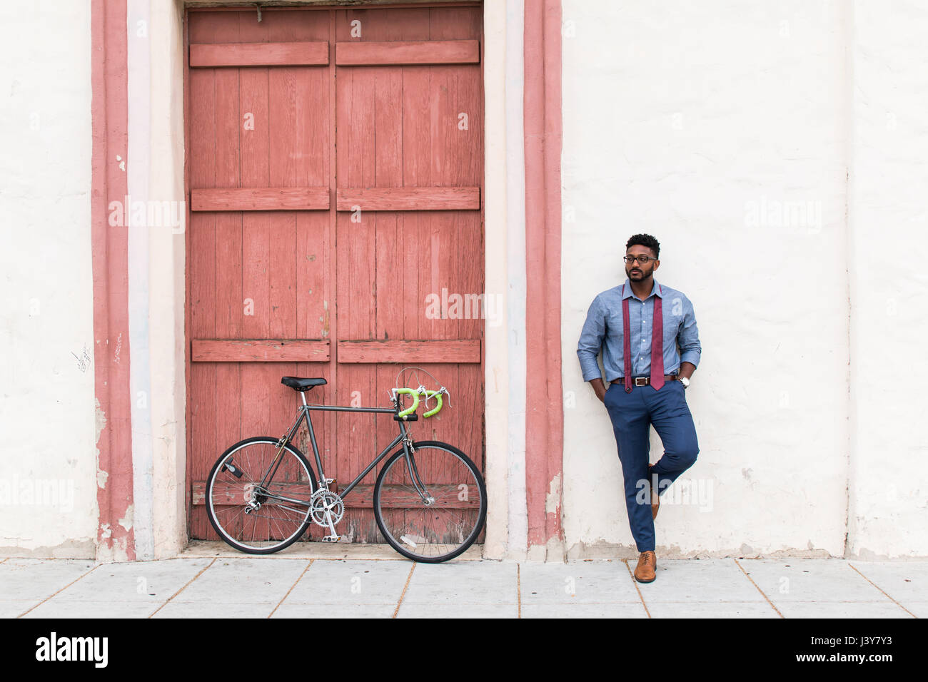 Junger Geschäftsmann Radfahrer warten Wand gelehnt Stockfoto
