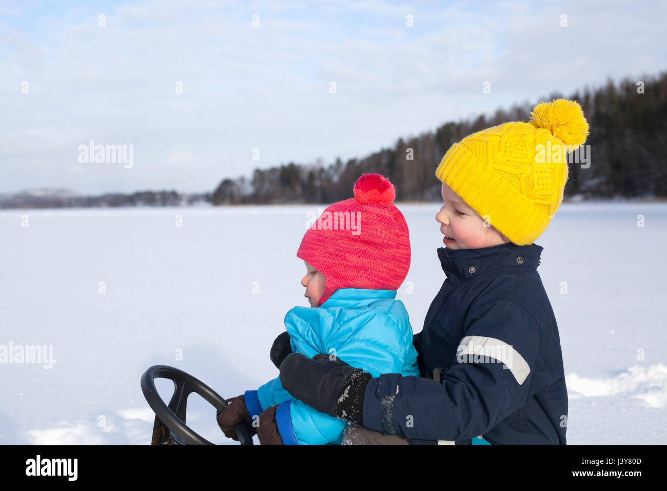 Zwei junge Brüder sitzen auf Schlitten im Schnee bedeckt Landschaft Stockfoto