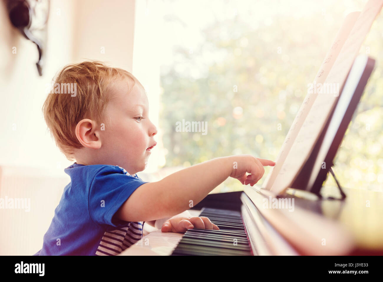 Junge Kleinkind zeigt auf musikalische Kerbe am Klavier Stockfoto