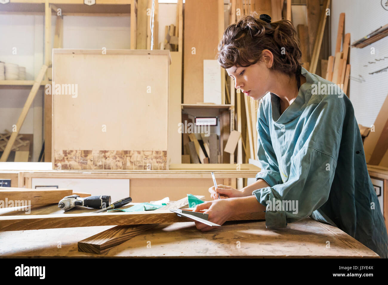 Junge Frau, die Messung von Holz in einem workshop Stockfoto