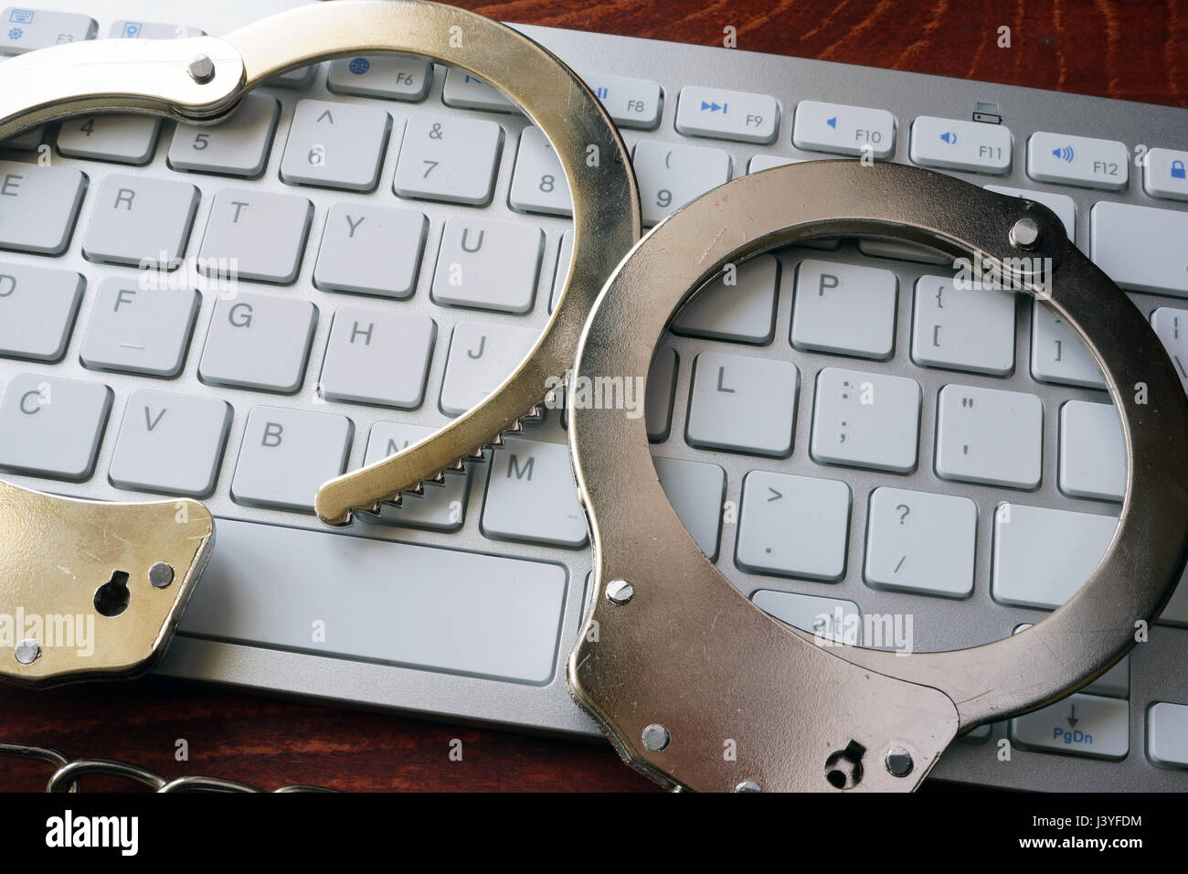 Hacking-Konzept. Handschellen auf der Tastatur. Stockfoto