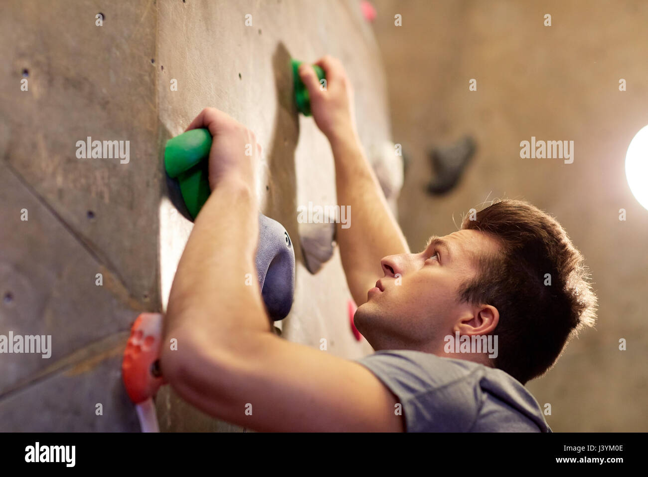 Junger Mann training Kletterhalle Wand Stockfoto