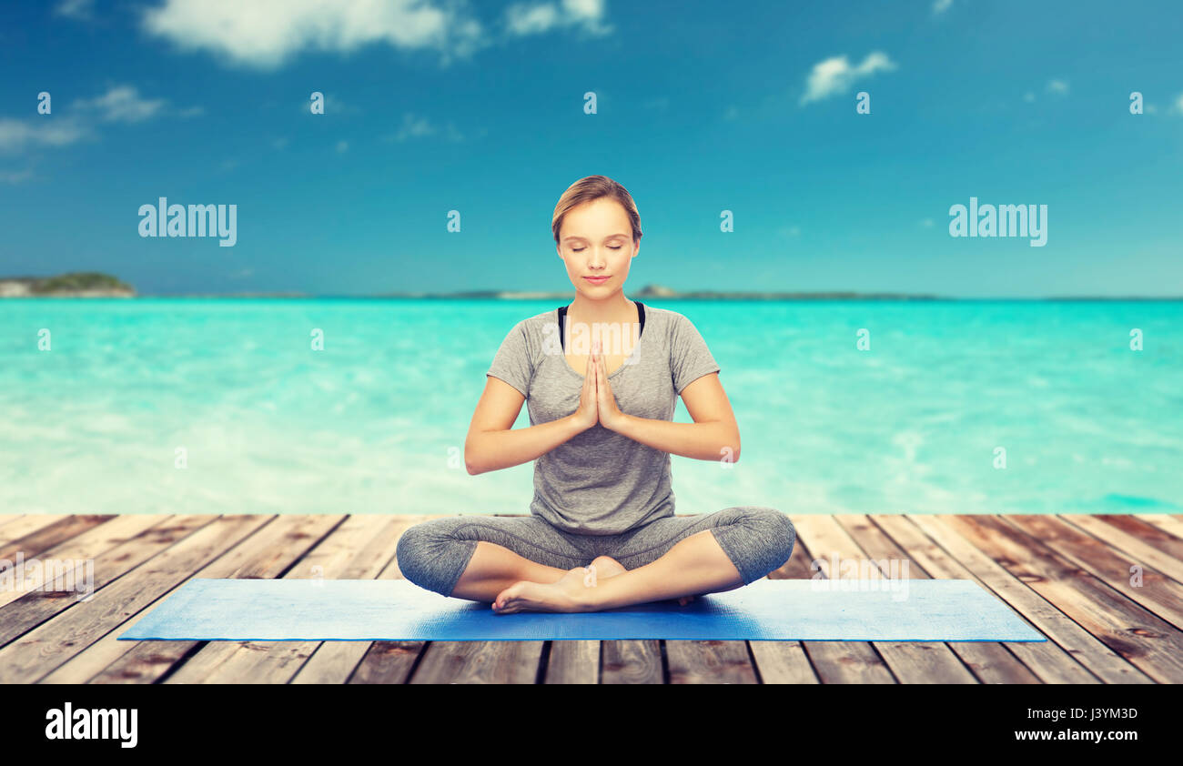 Frau macht Yoga Meditation in Lotus Pose auf Matte Stockfoto