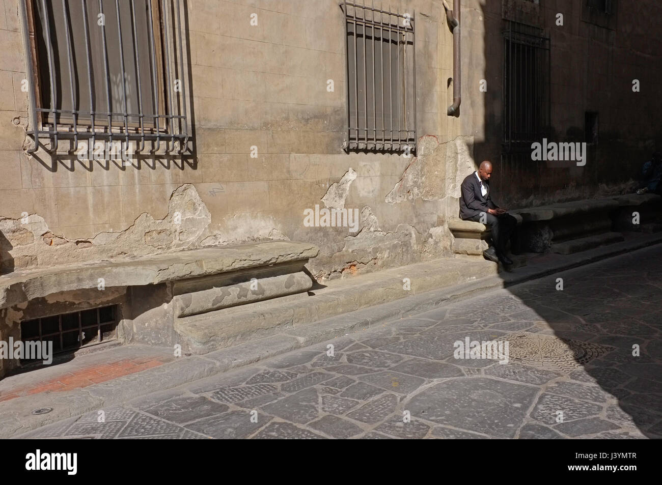 Ein Mann in der Sonne und im Schatten sitzen in Florenz Stockfoto