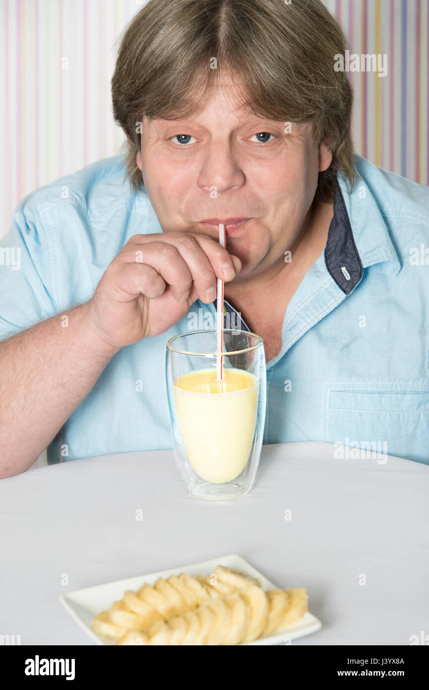 Sympathischer Mann trinkt Milch-Shake Banane mit Stroh Stockfoto