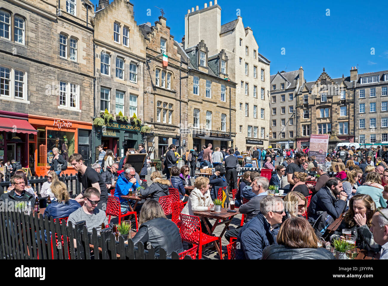Touristen und Einheimische gleichermaßen draußen essen und genießen einige Frühsommer Sonne in Grassmarket, Edinburgh, Schottland, Großbritannien. Stockfoto