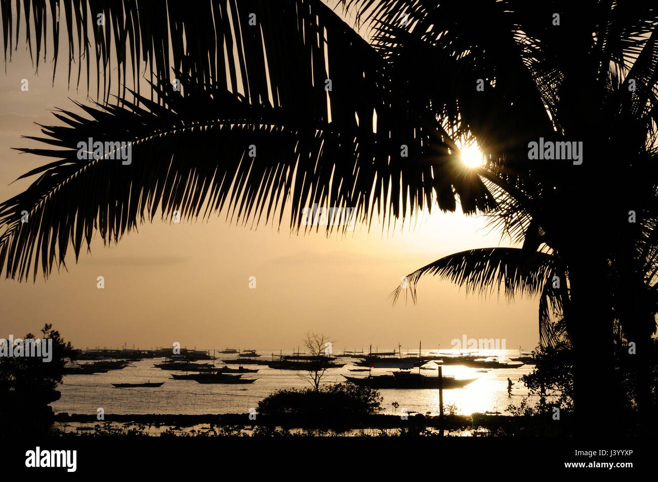 Goldener Sonnenuntergang am Strand von Danao mit Booten vor Anker im Hafen, Panglao, Philippinen Stockfoto