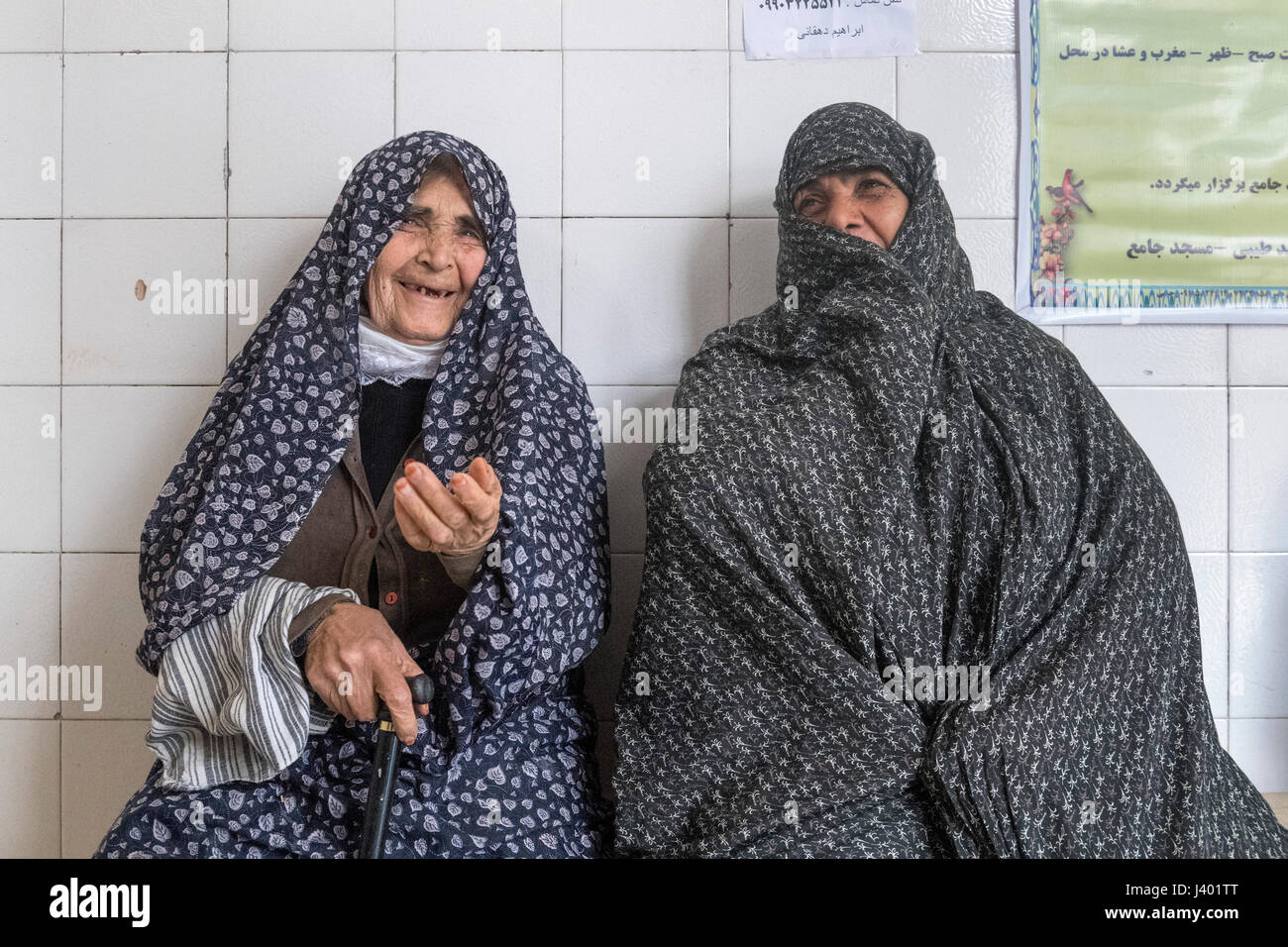 Zwei weibliche Kunden tragen Tschador warten frische Brötchen beim Bäcker, Rooieen (Ruine), einem traditionellen Dorf Nord-Chorasan, IRAN- Stockfoto