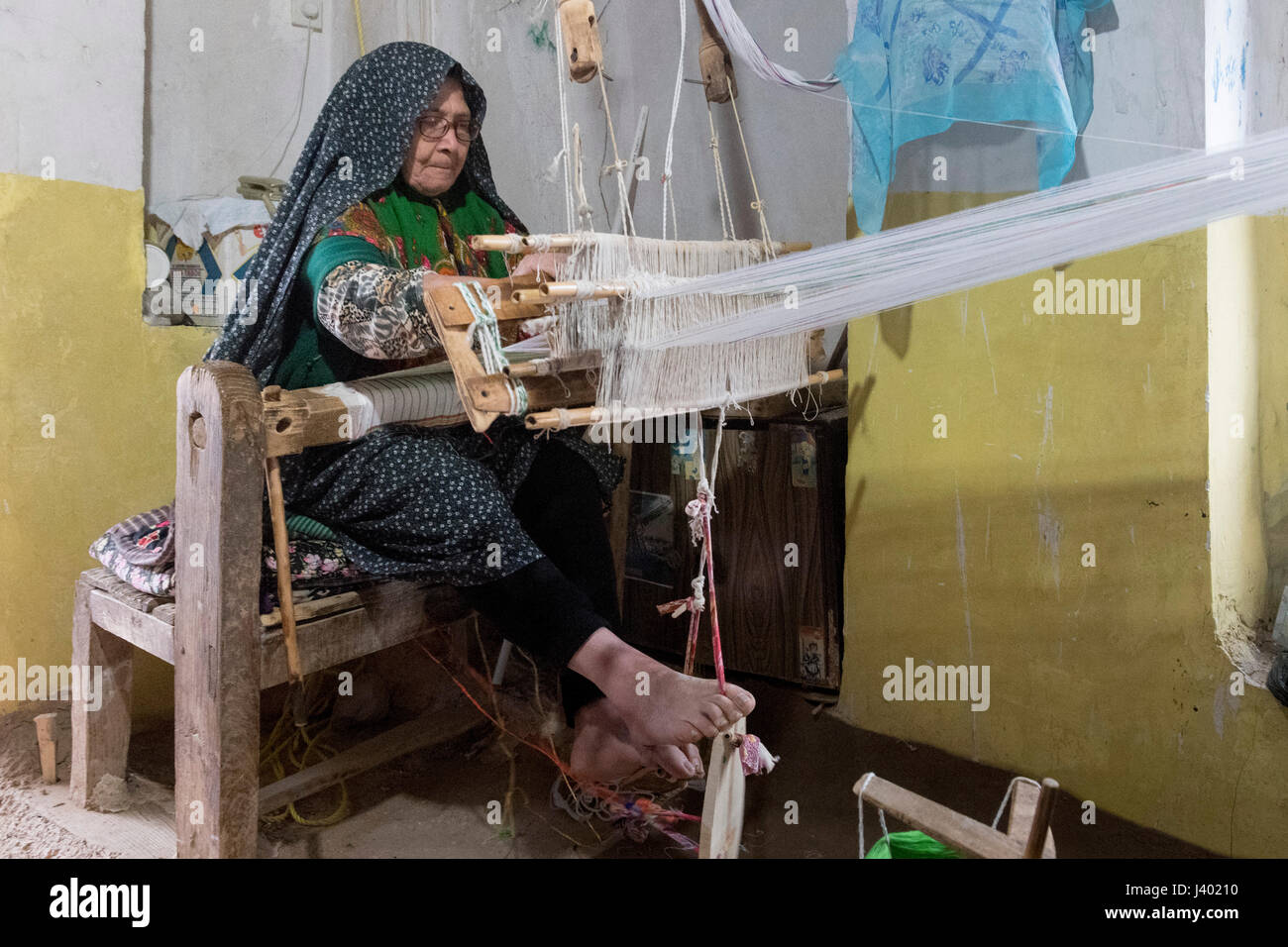 Begeisterte ältere Dame weben 8 Stunden am Tag für nur $30 Monat, Rooieen (Ruine), ein traditionelles Dorf, Nord-Chorasan, IRAN - 01 / Stockfoto